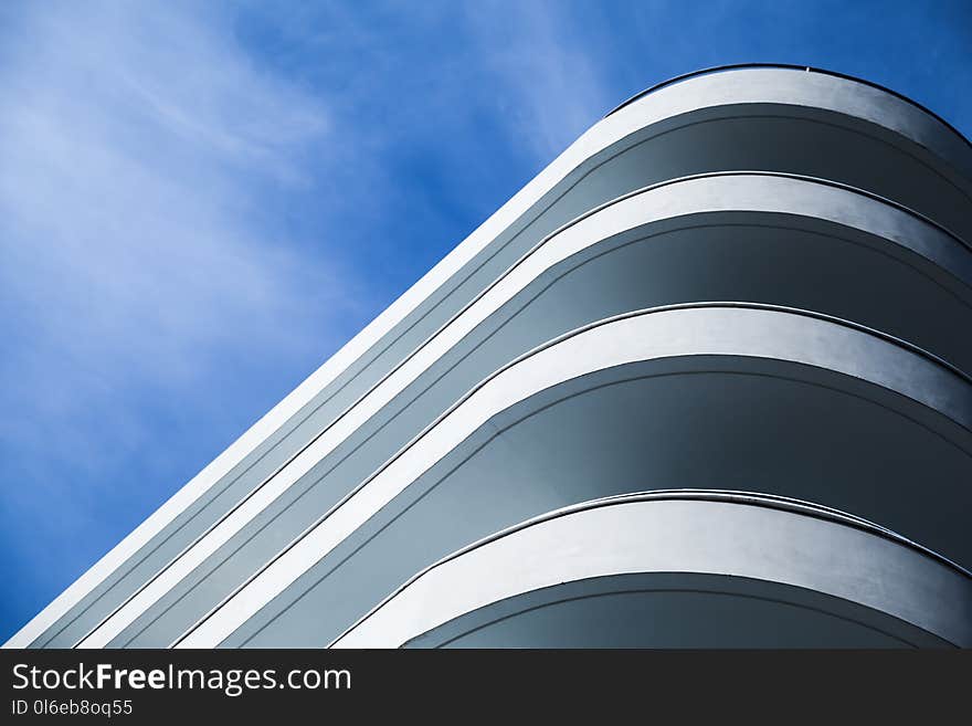 Abstract modern architecture, round white concrete facade under blue cloudy sky