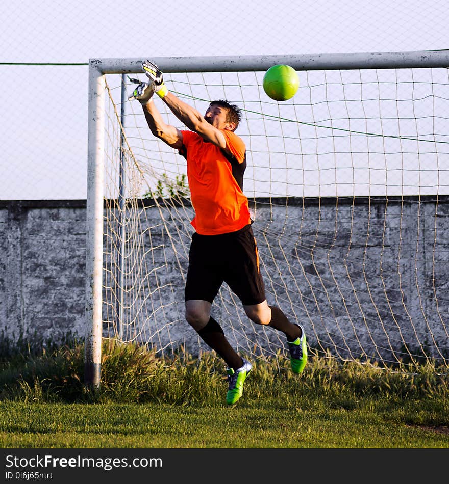 The goalkeeper or goalie is jumping to soccer ball on the playing field. The goalkeeper or goalie is jumping to soccer ball on the playing field.