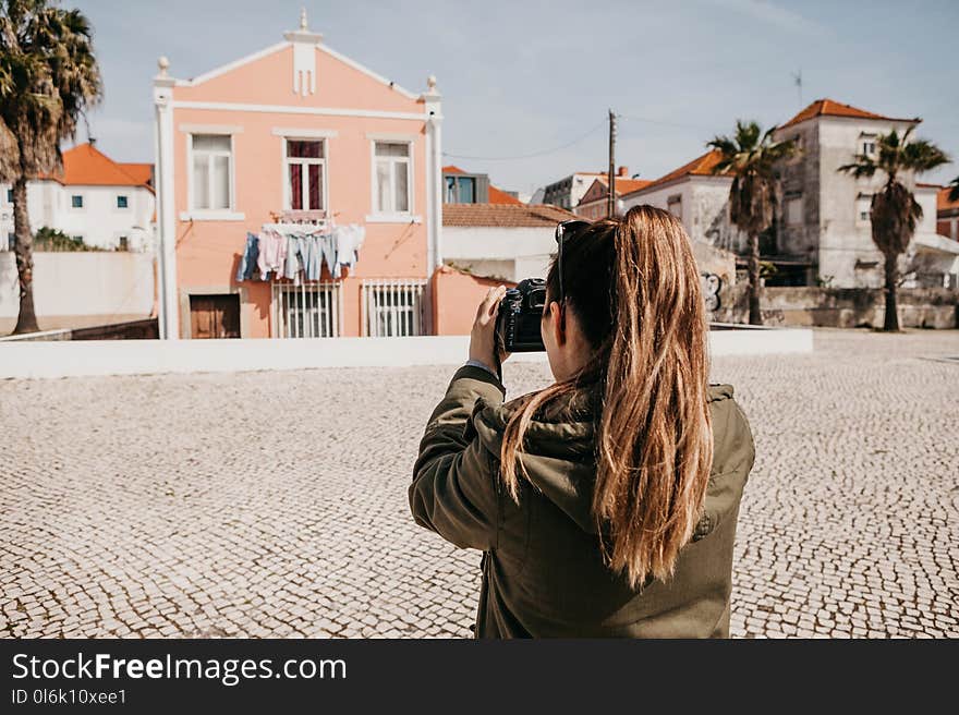 A street photographer or a young woman takes pictures of authentic houses in Lisbon in Portugal. A professional