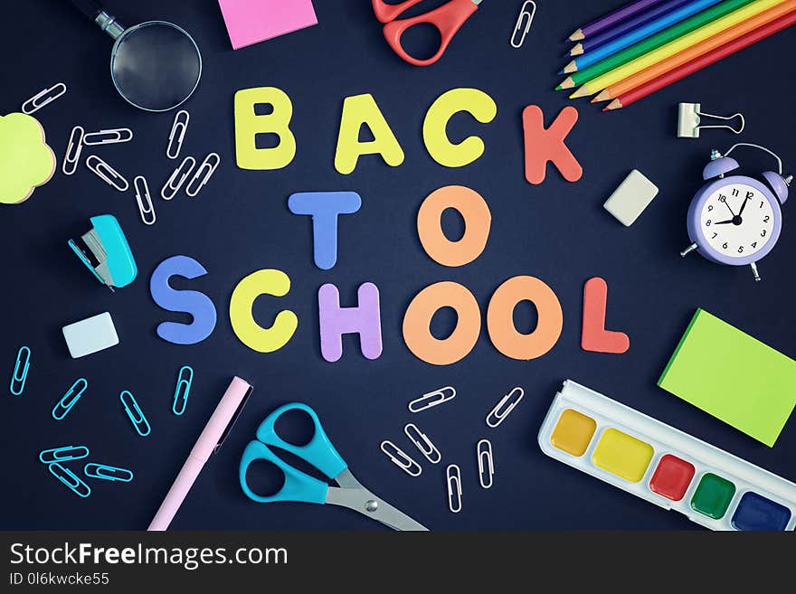 On a black background, school and office supplies are chaotically arranged. In the center is the inscription BACK TO SCHOOL, made in multi-colored letters. Beautiful pictures on top, layout.