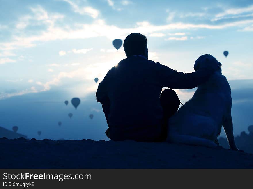 Man with a dog looking at the flight of passenger balloons in Ca