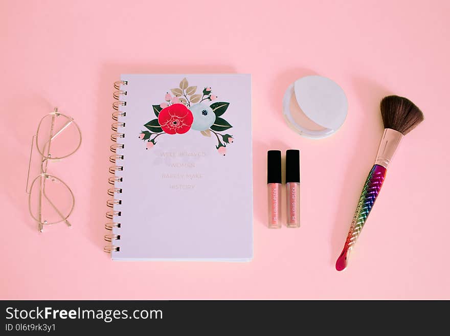 Flat lay Photography of Notebook Near Eyeglasses and Make-up