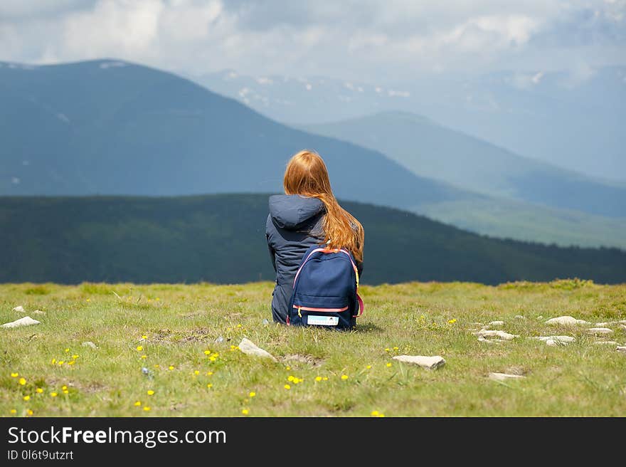 Person Wearing Gray Hooded Jacket Sitting on Grassy Field