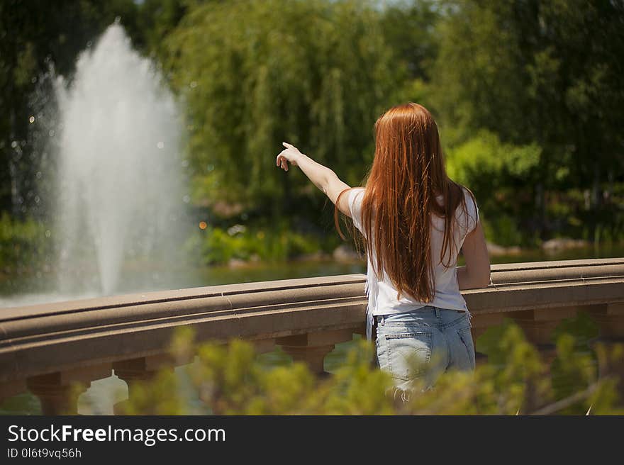 Shallow Focus Photo of Woman Standing in Front of Body of Water With Fountain