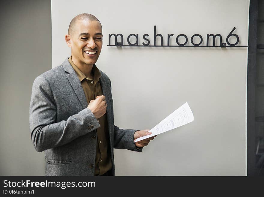 Man Wearing Grey Notched Lapel Suit Jacket Holding White Printer Paper While Standing