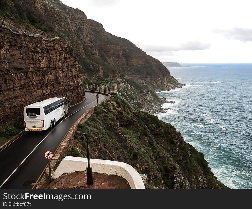 White Bus on Road Near Cliff