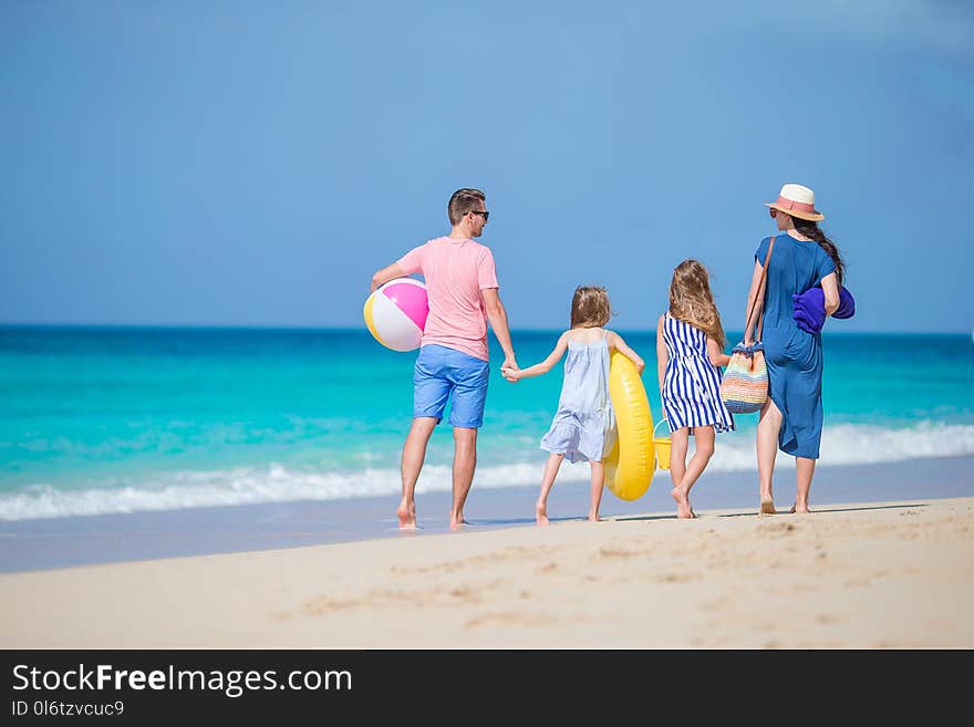 Happy beautiful family of four on white beach walking together. Happy beautiful family of four on white beach walking together