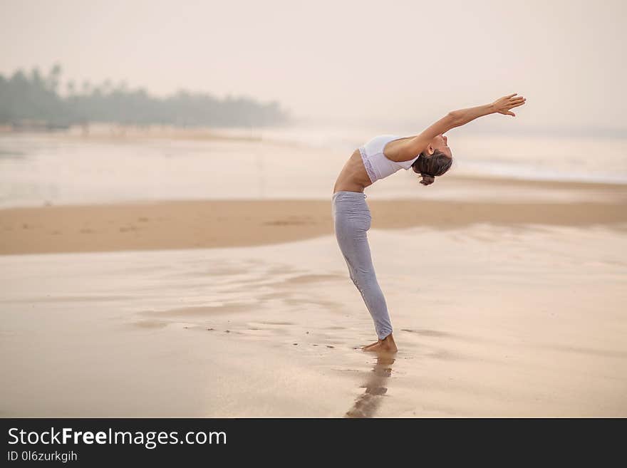 Caucasian woman practicing yoga at seashore of tropic ocean