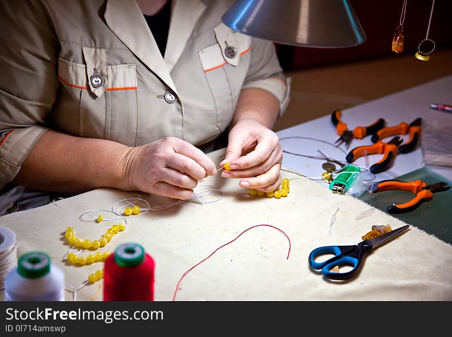 The hands of the jeweler. Making amber jewelry by the master. The hands of the jeweler. Making amber jewelry by the master