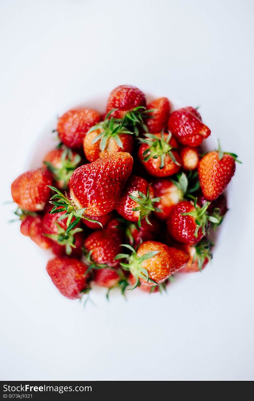 A ripe tasty strawberry lies in a plate on a white background. Isolated. Summer still life. A ripe tasty strawberry lies in a plate on a white background. Isolated. Summer still life.