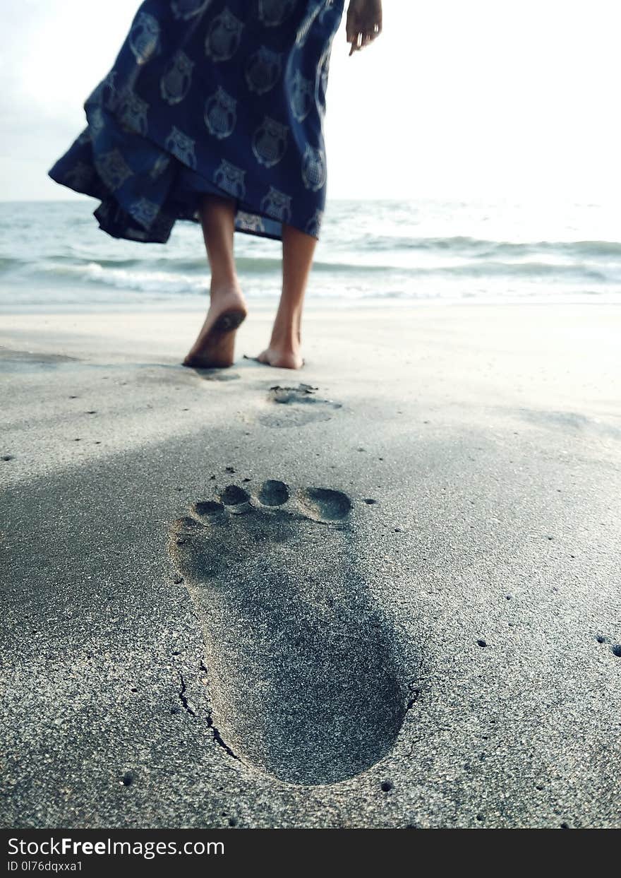 Photo of Woman Walking Barefoot on Seashore