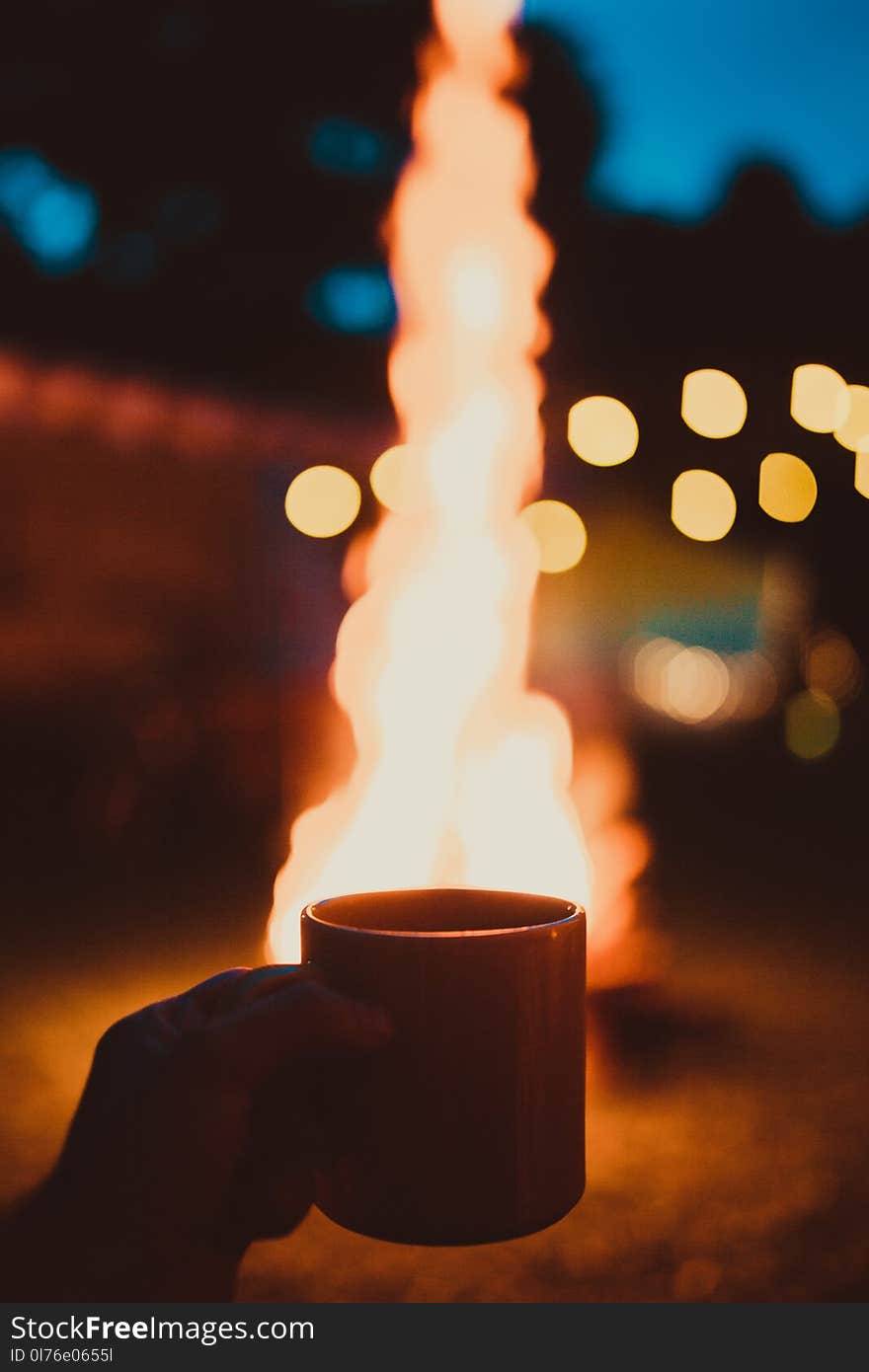 Photo of Person Holding Mug and Watching Bonfire