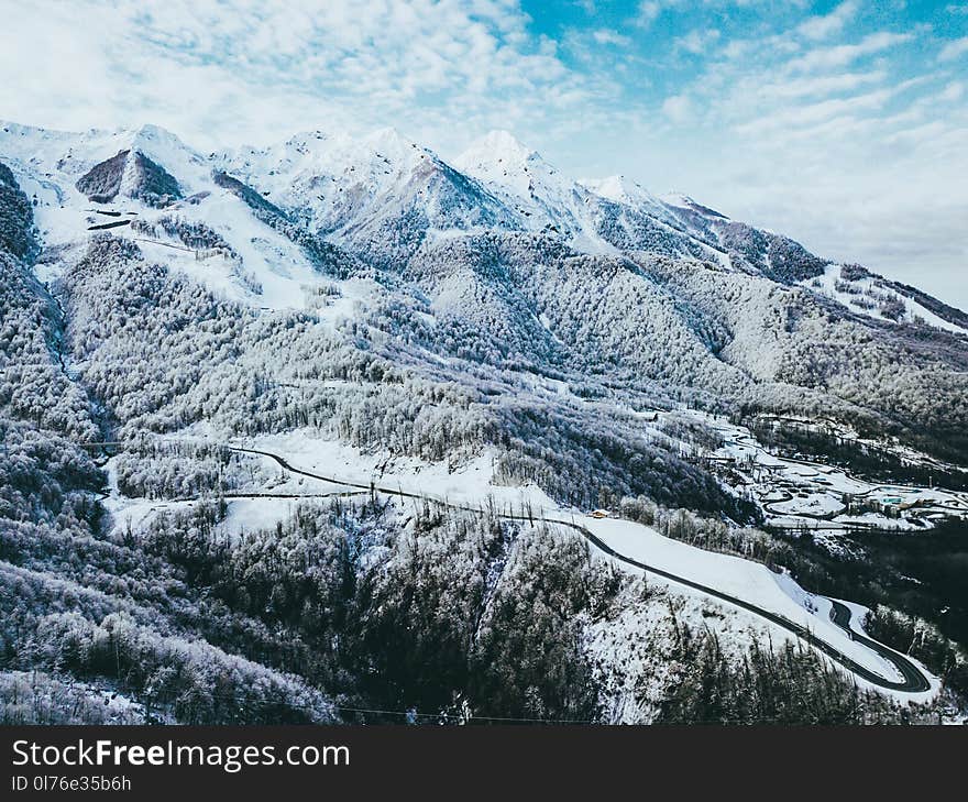 Mountains Covered in Snow Under Cloudy Sky