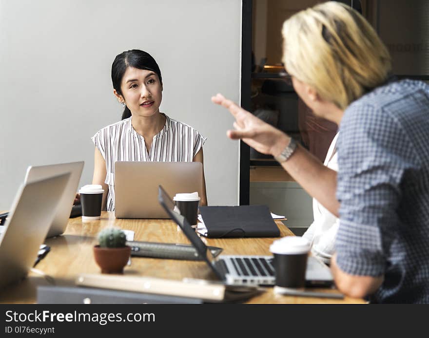 Men Talking to a Woman Sitting in Front of Silver Laptop Computer