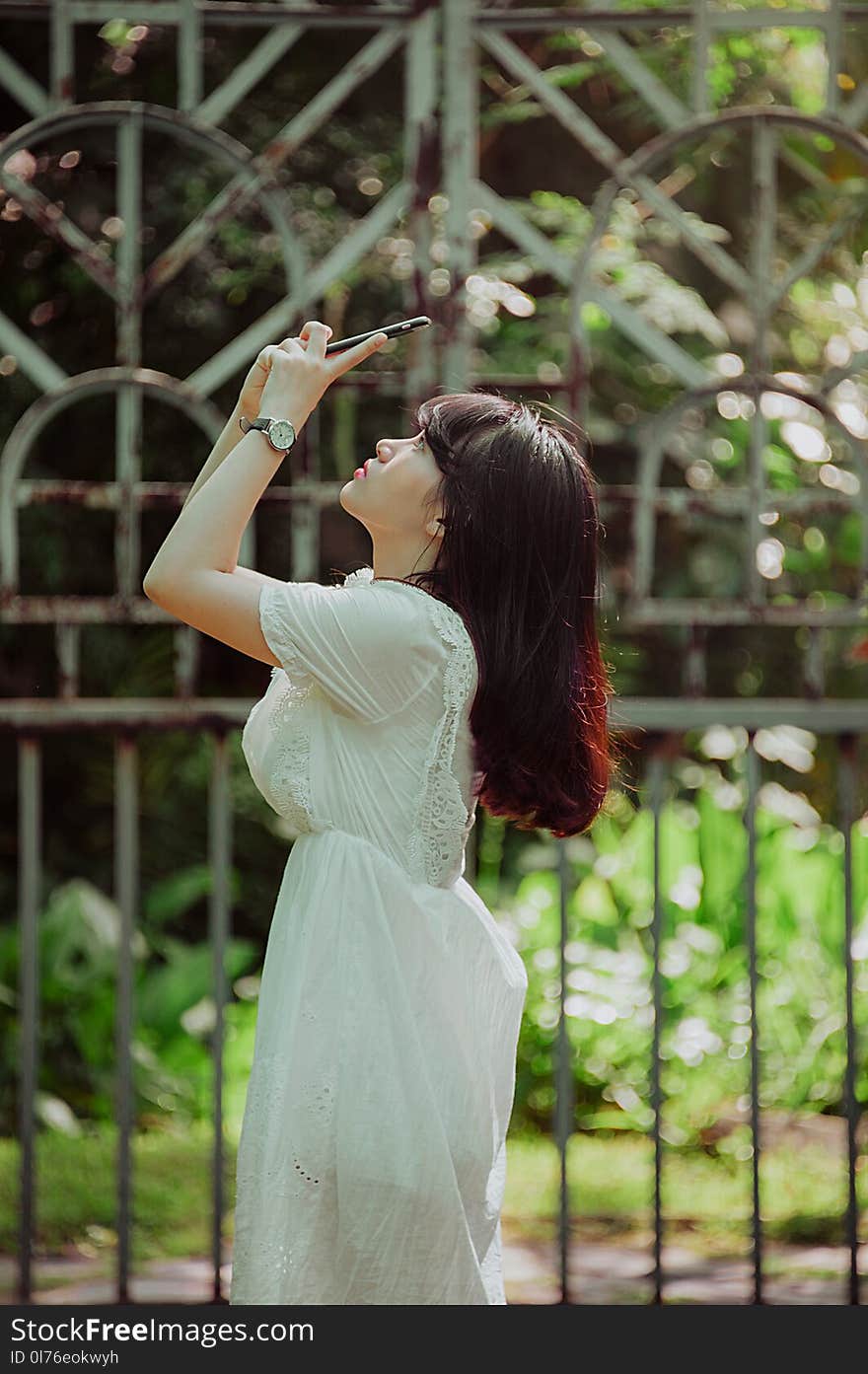 Woman Wearing White Lace Dress Staring in Her Smartphone