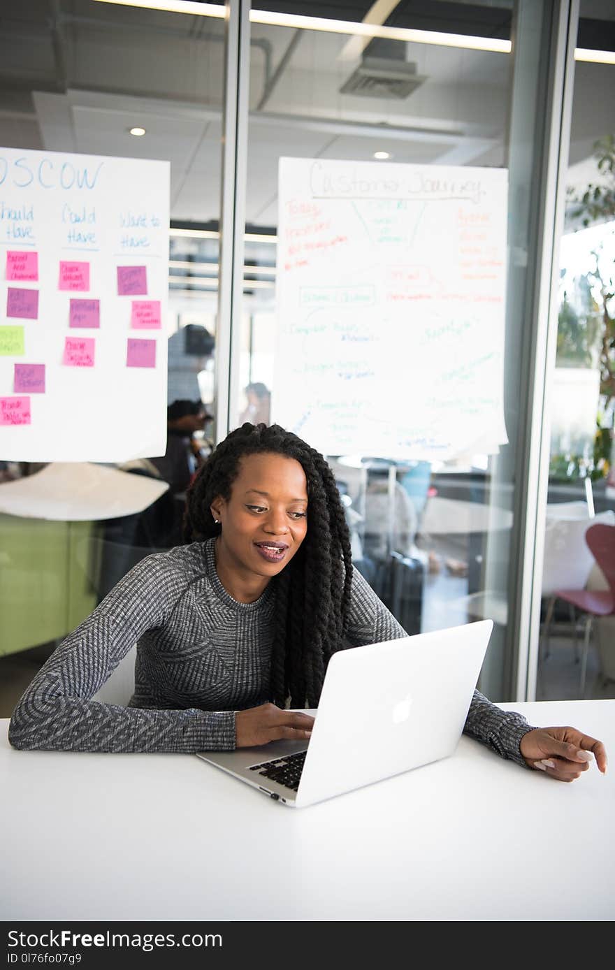 Woman in Gray Sweater Sitting in Front of Laptop Computer on Table