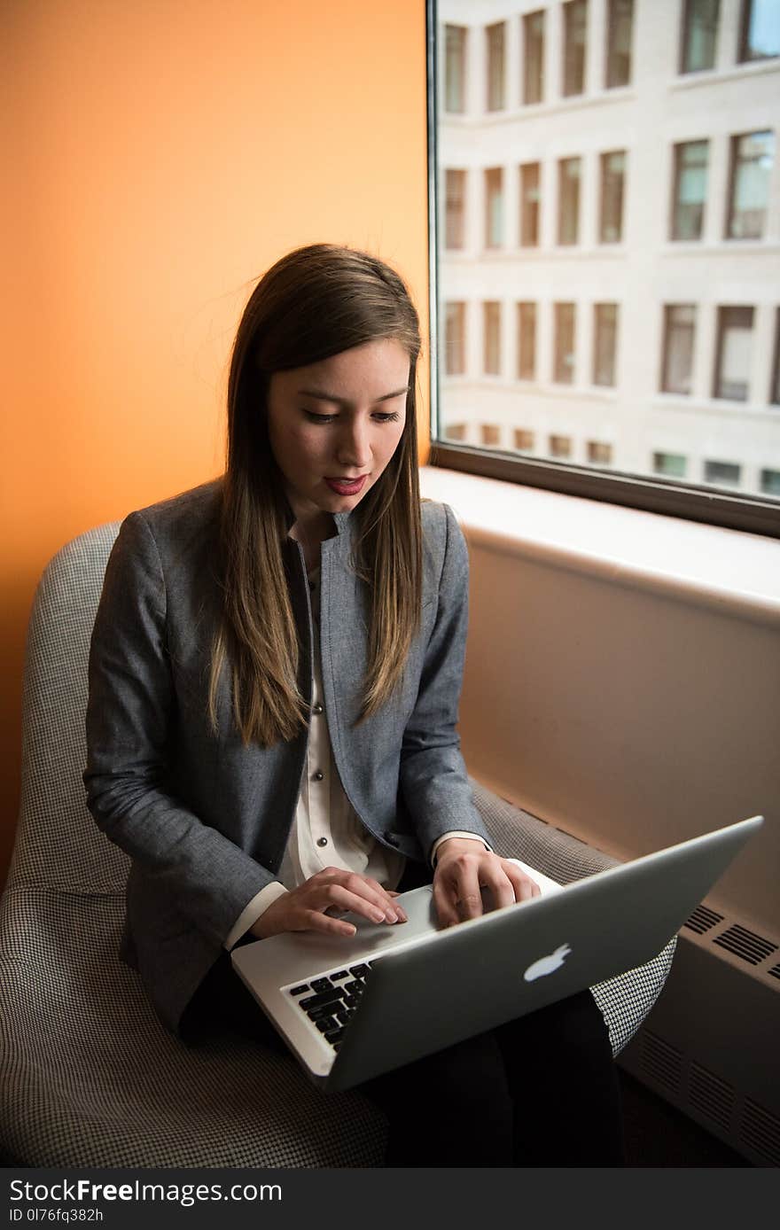 Photo of Woman Sitting on Chair and Typing on Silver Macbook