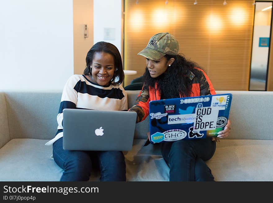 Two Woman Sitting On Sofa While Using Laptops