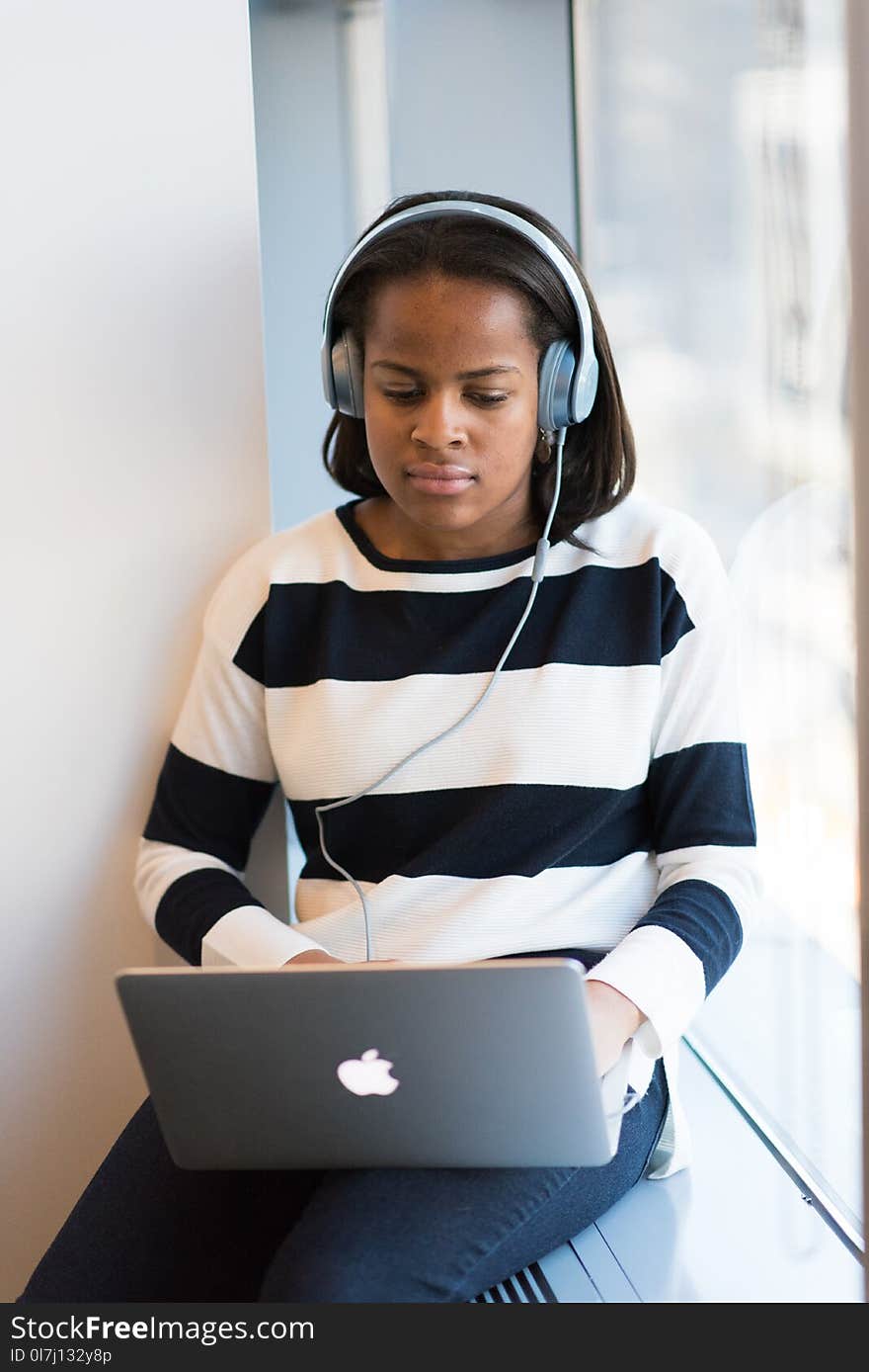 Woman Listening Through Headphones Using Macbook