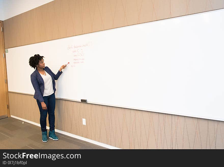 Woman Wearing Black Blazer Holding Pen Pointing White Marker Board