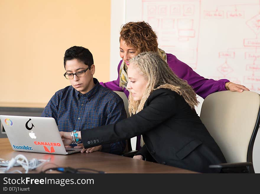 Closeup Photo of Three Person Looking at Macbook Air