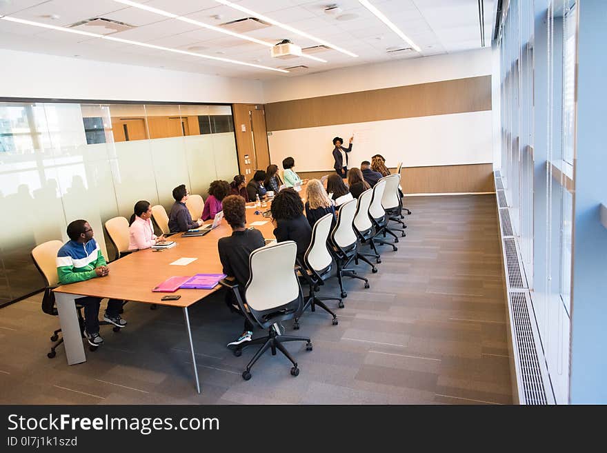 People Sitting on Beige Rolling Chairs on Brown Wooden Table Inside Room