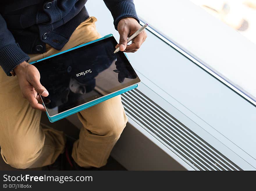 Person Wearing Brown Pants Holding Black Tablet Computer