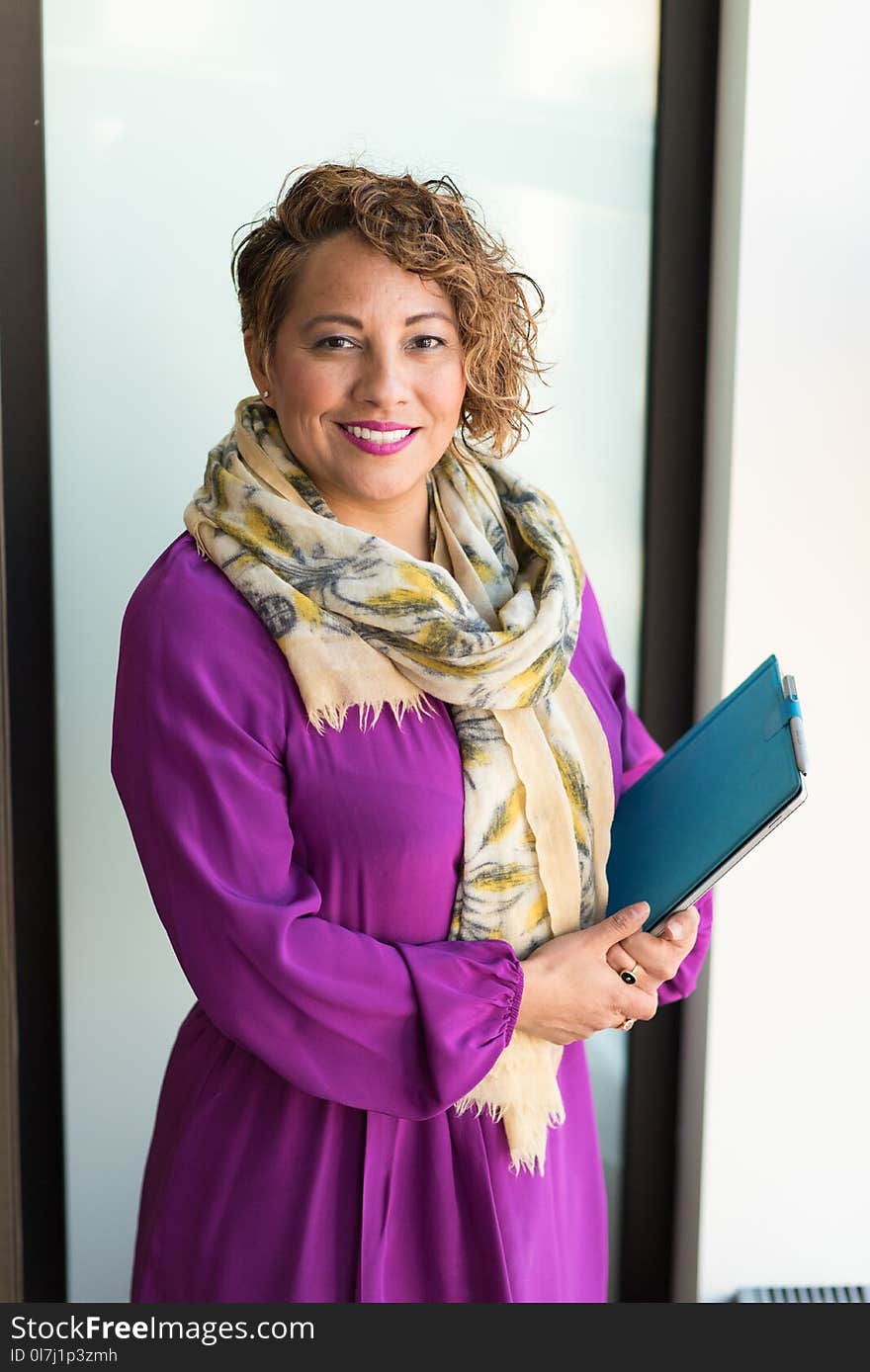 Woman Smiling and Holding Teal Book