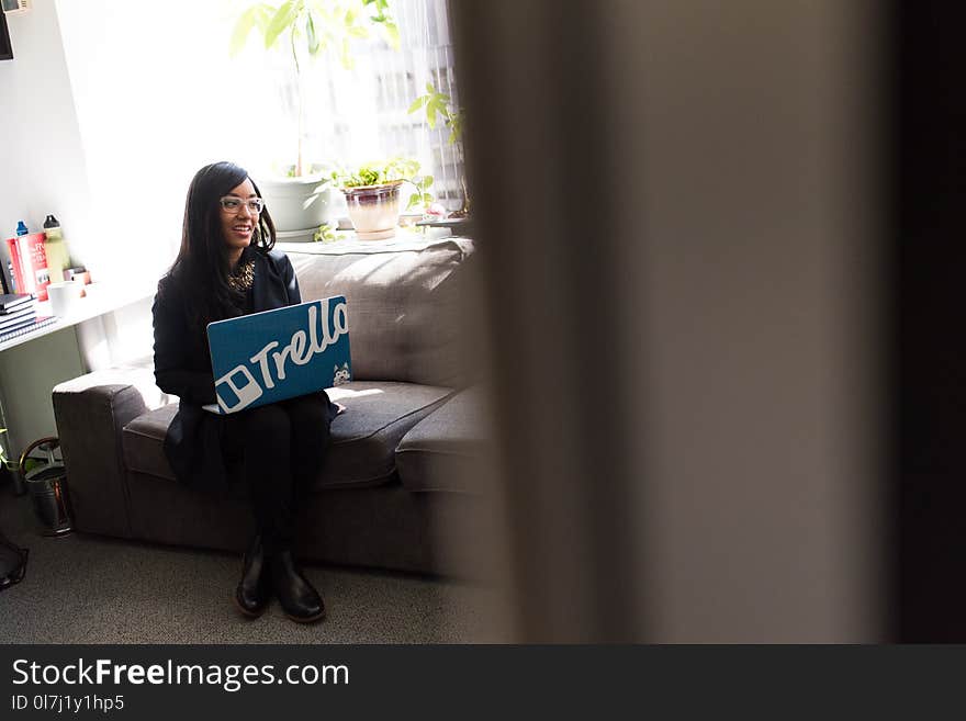 Woman Using Blue and White Laptop Sitting on Sofa