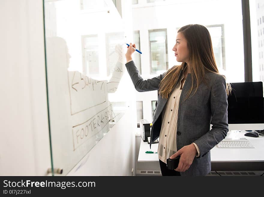 Woman Wearing Gray Blazer Writing on Dry-erase Board