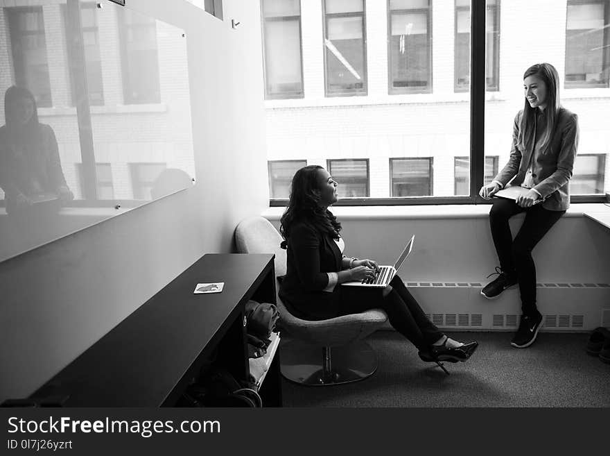 Grayscale Photo of Woman Talking to Her Colleague