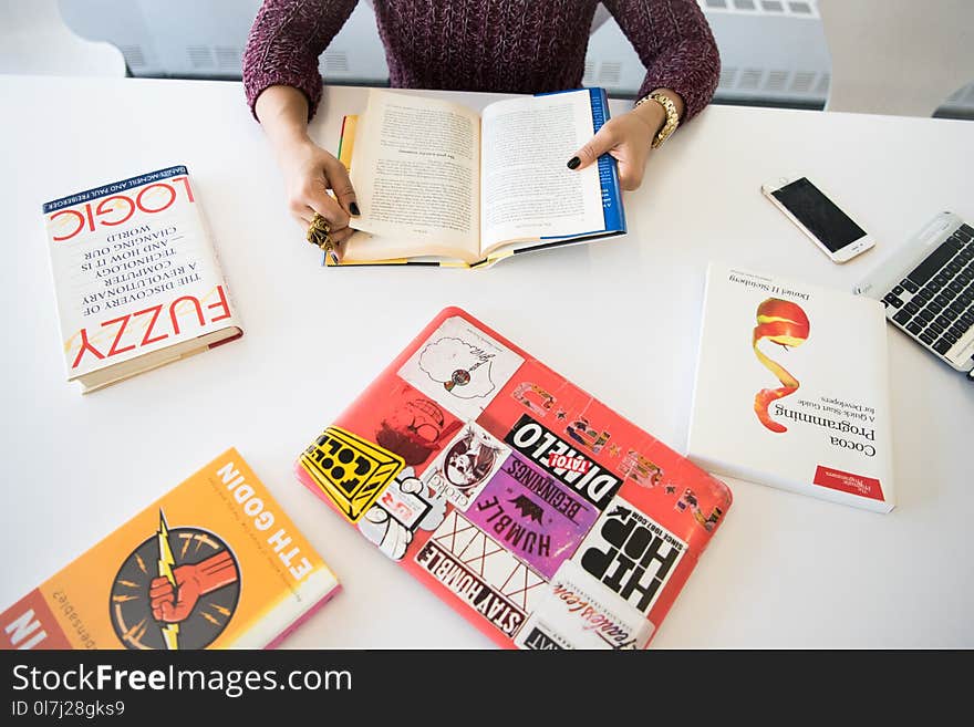 Person Holding Open Book on Table Inside Room