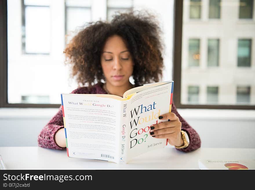 Sitting Woman While Reading Books Near Table