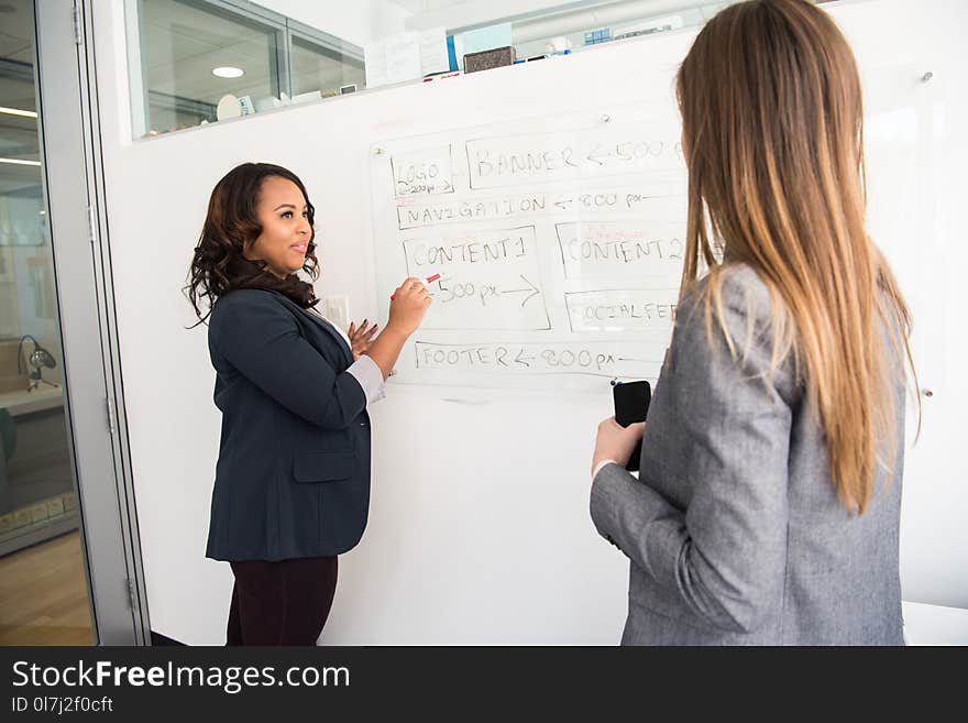 Woman in Black Blazer Looking at Woman in Grey Blazer