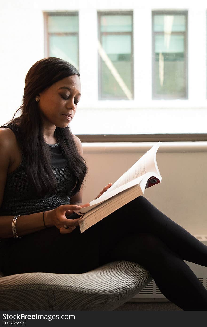 Closeup Photo of Woman Sitting on Chair While Reading Book