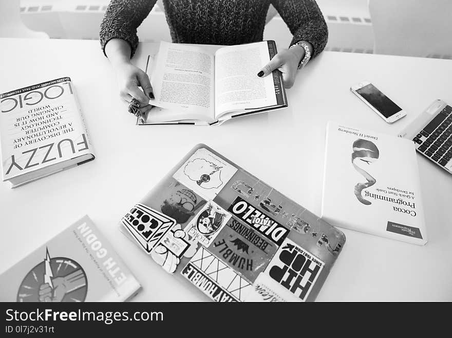 Grayscale Photo of Person Sitting Near Table With Books