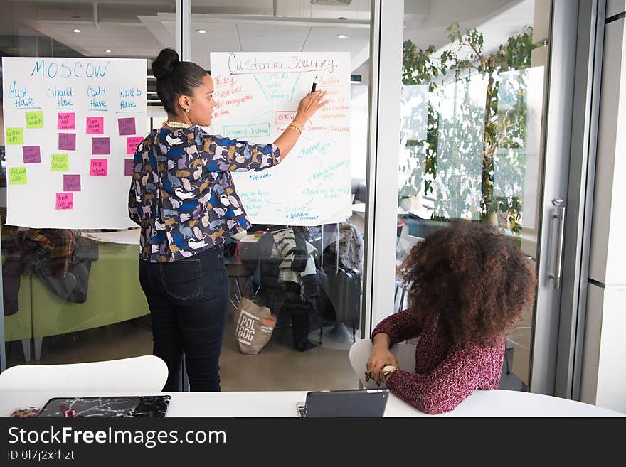 Two Women Having a Meeting Inside Glass-panel Office