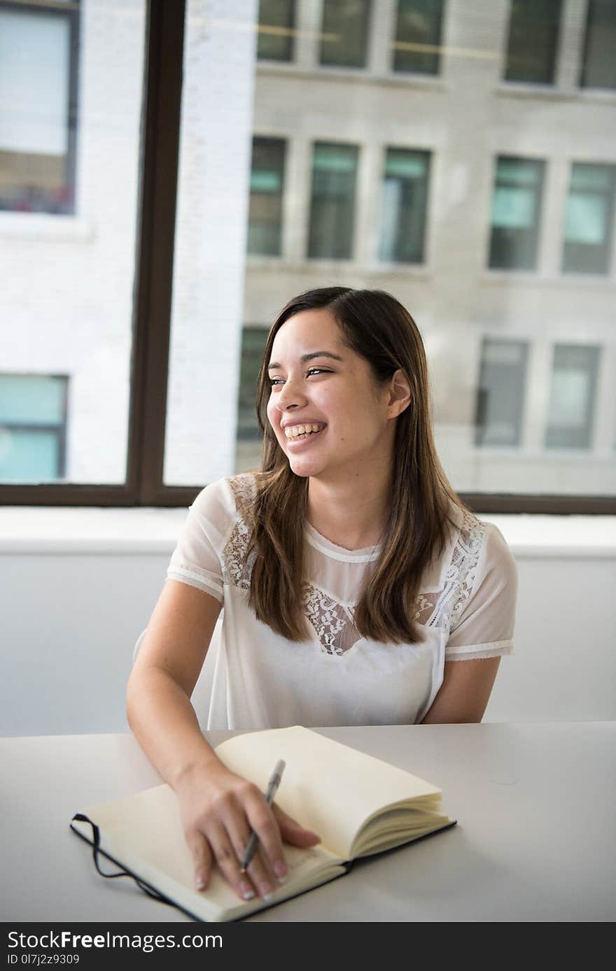 Woman Wearing White T-shirt Holding Notebook and Pen