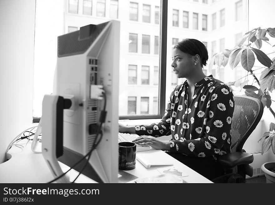 Gray Scale Photography of Woman Sitting on Armchair Facing Computer Monitor