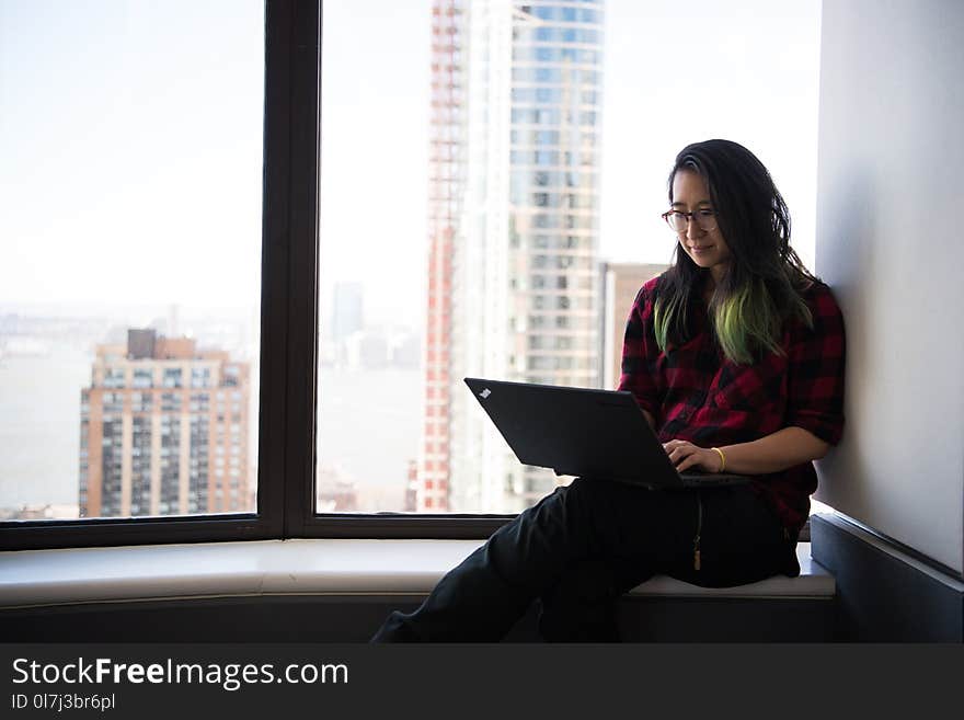 Woman Wearing Red Elbow-sleeved Shirt and Black Pants Sitting Beside Window