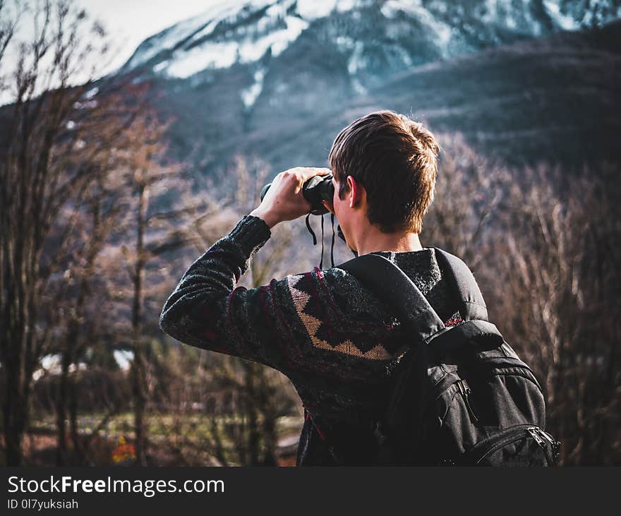 Man Using Black Binoculars Near Forest Trees at Daytime