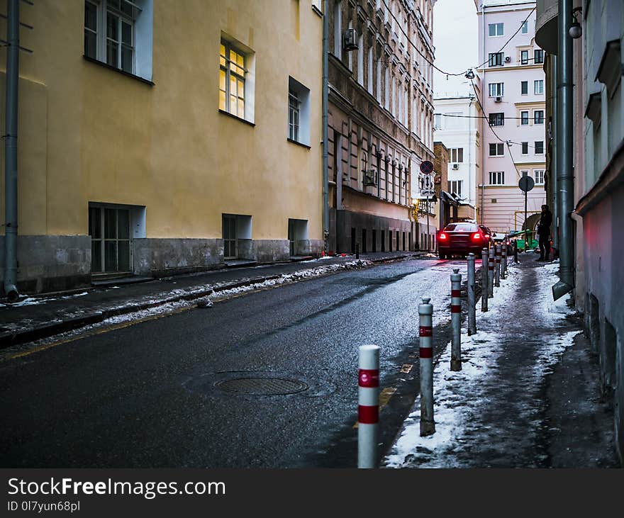 Black Car Crossing Asphalt Road Between Buildings