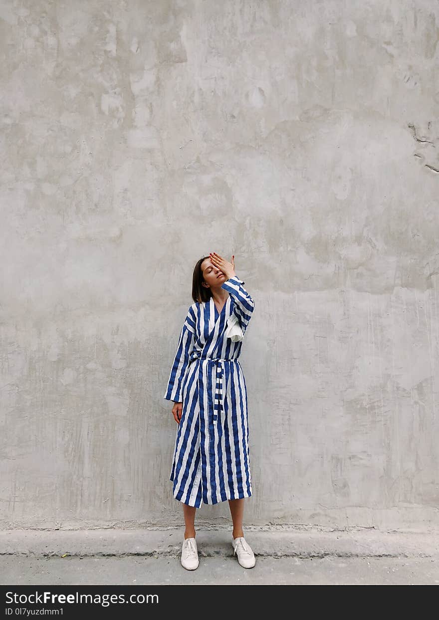 Woman in Blue and White Striped Dress Covering Her Left Eye