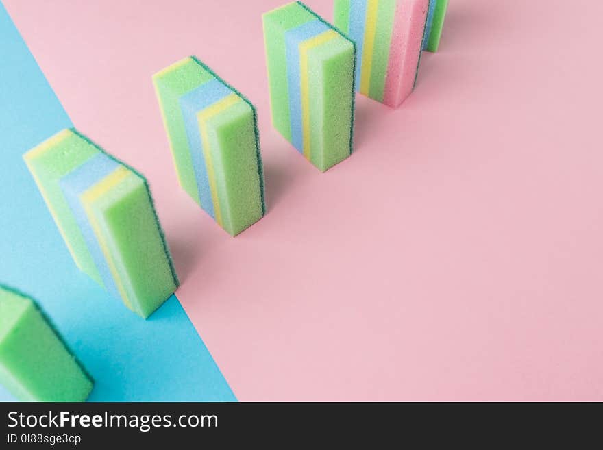 line of colorful washing kitchen sponges, on blue and pink