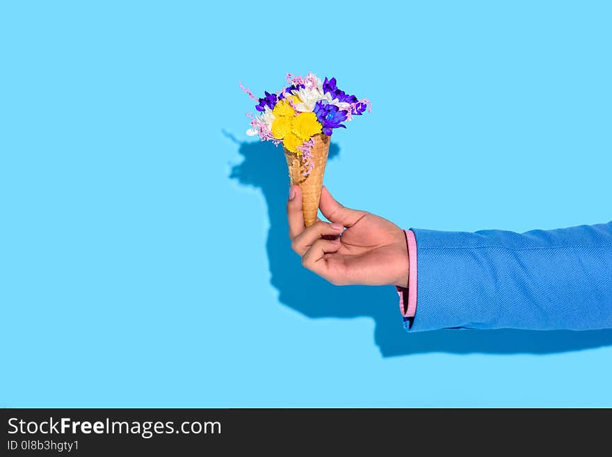 Cropped image of man hand holding flowers on blue background