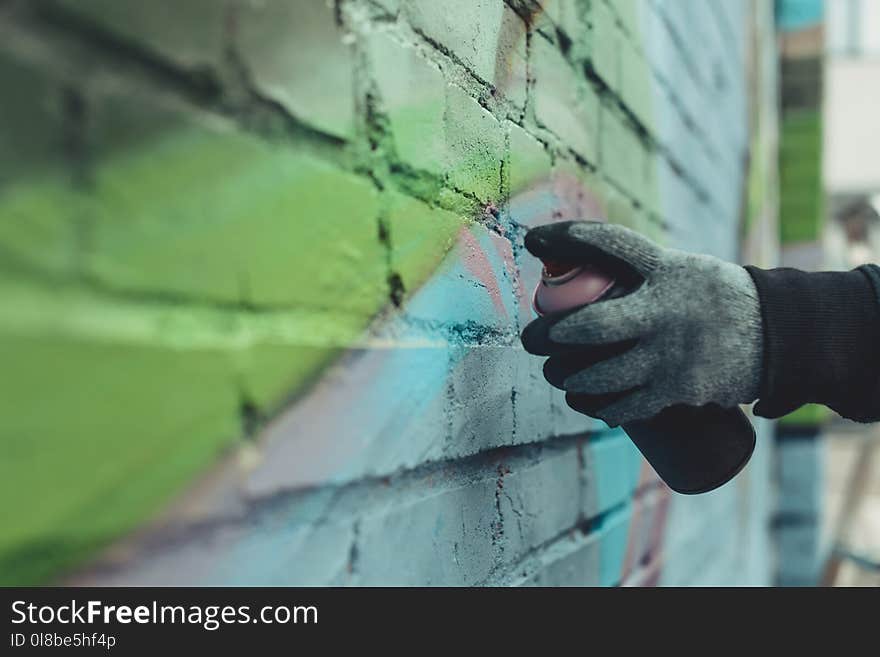 cropped view of man painting colorful graffiti on wall