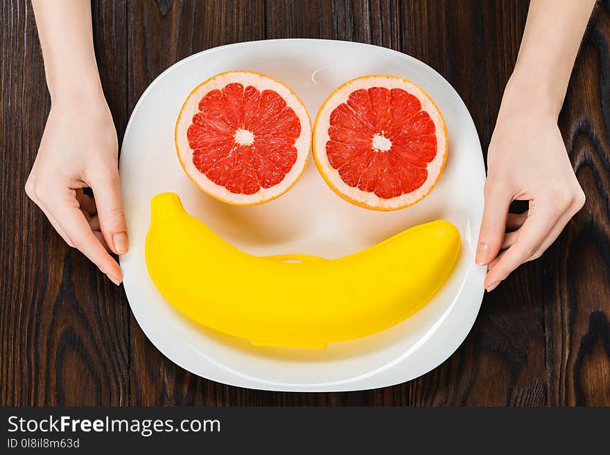 cropped shot of woman holding plate with halved grapefruit and banana case