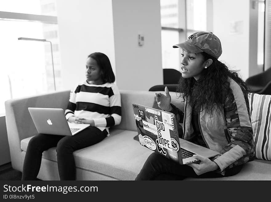 Two Women Sitting on Sofa Holding Laptop Computers