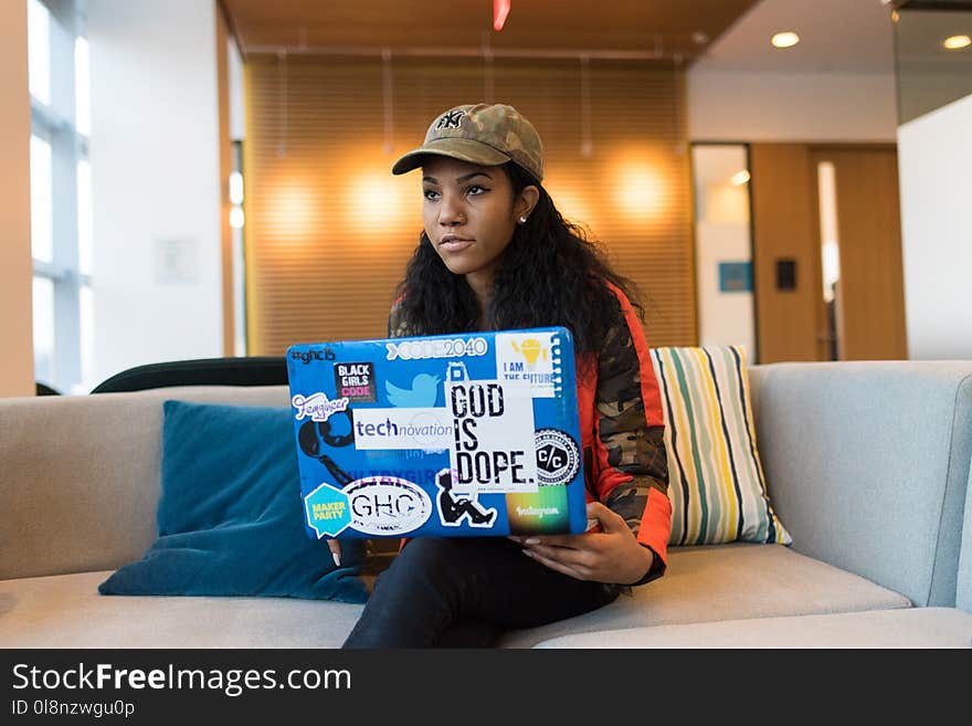 Woman Holding Blue Box While Sitting on White Couch