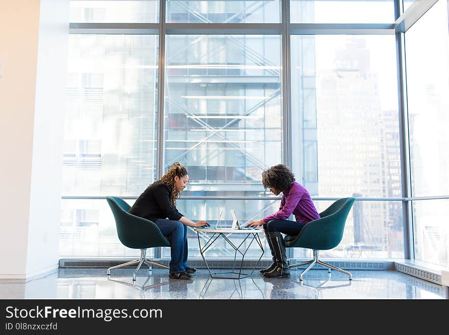 Two Woman Sitting Near Green Padded Chair